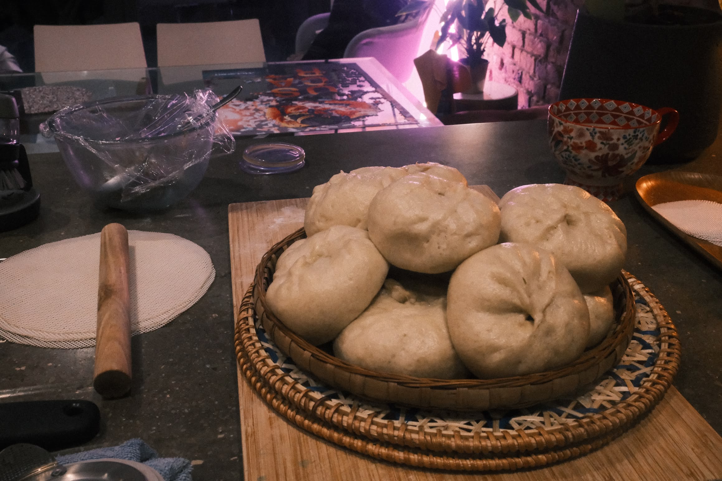 A kitchen work surface shows evidence of cooking. In the forground a plate of filled buns.