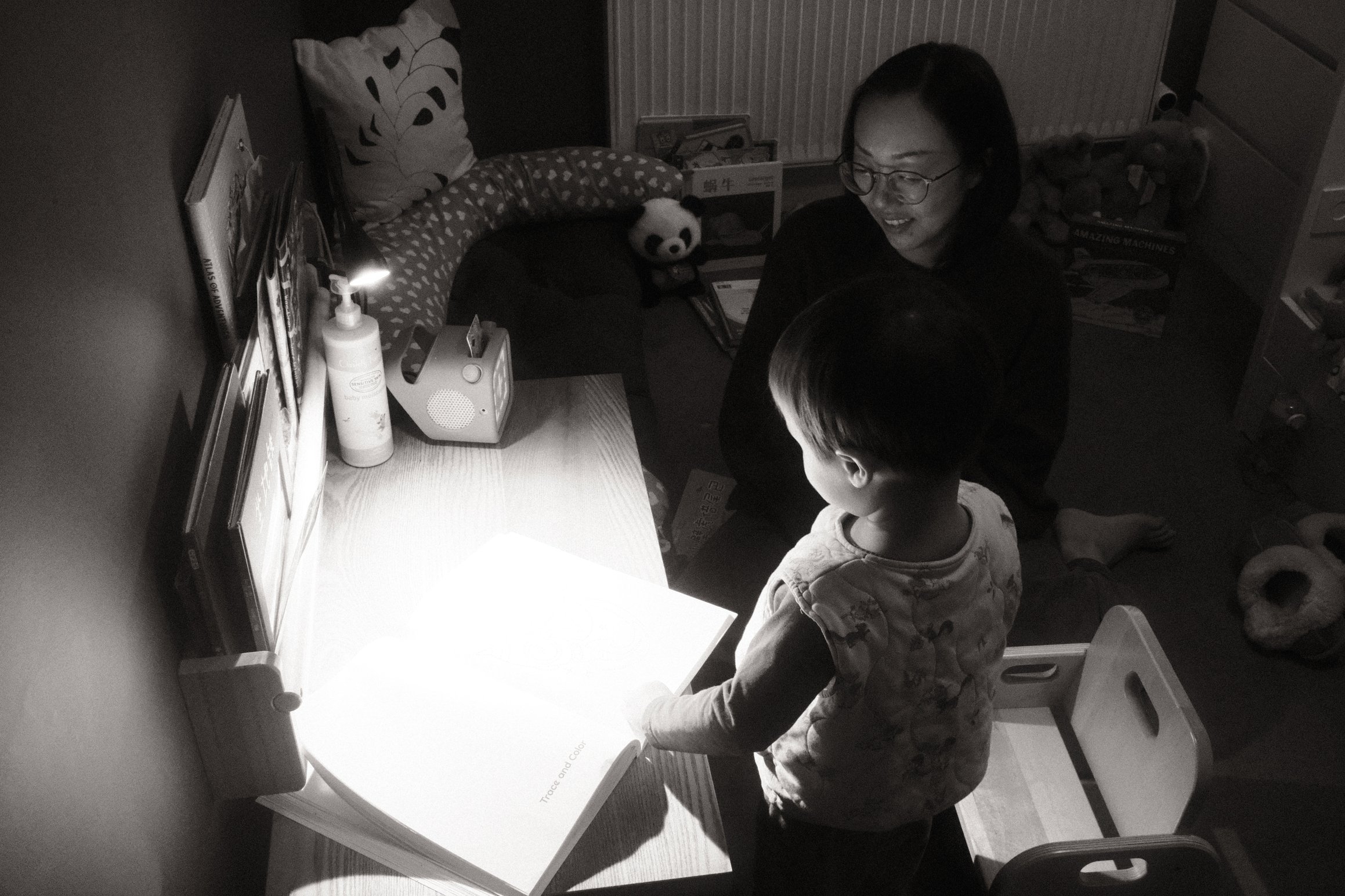 a black and white photo of a young boy and his mother looking at a book