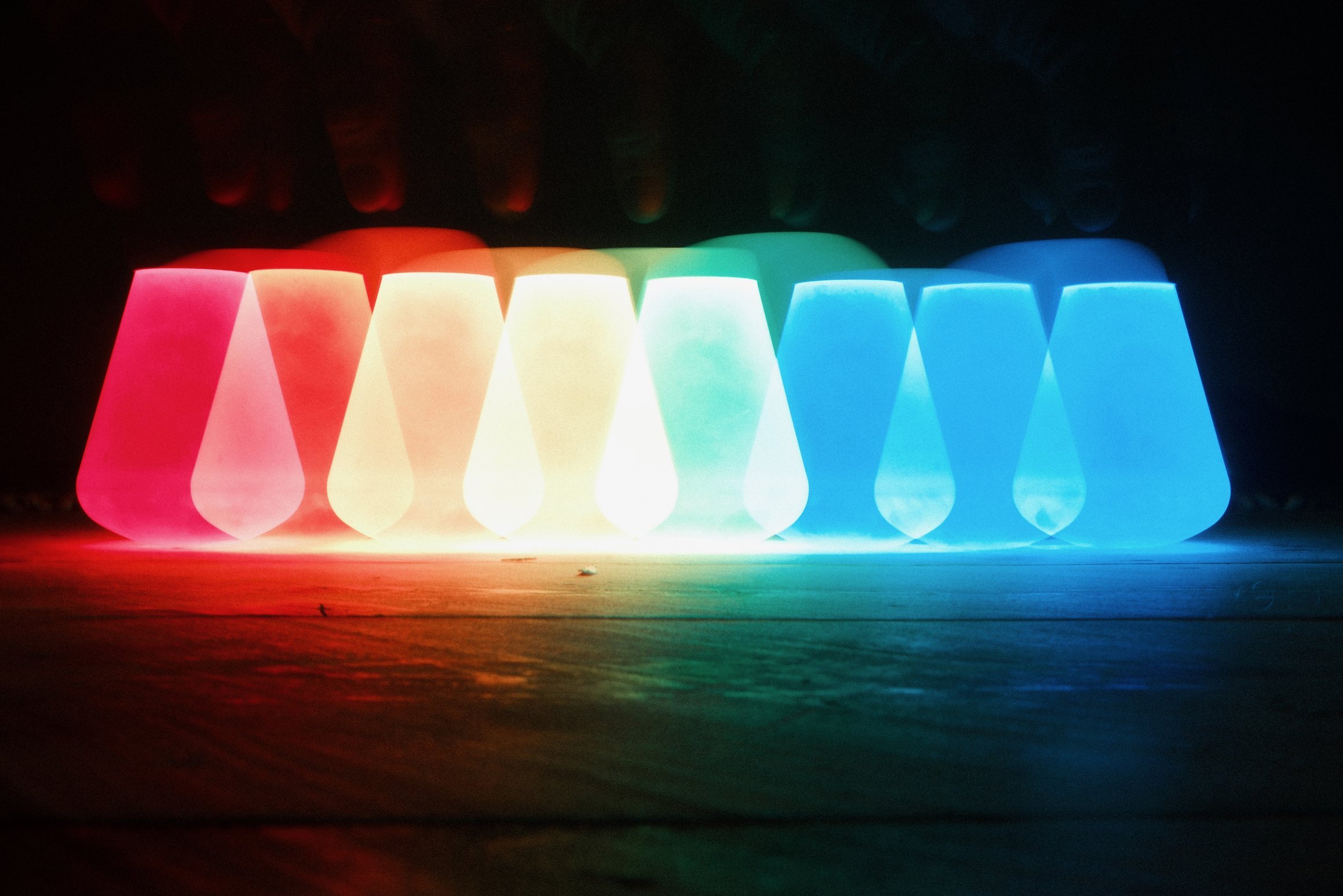 a long exposure image shows the blurred outline of a lightbulb moving across the image changing from red to blue as it does