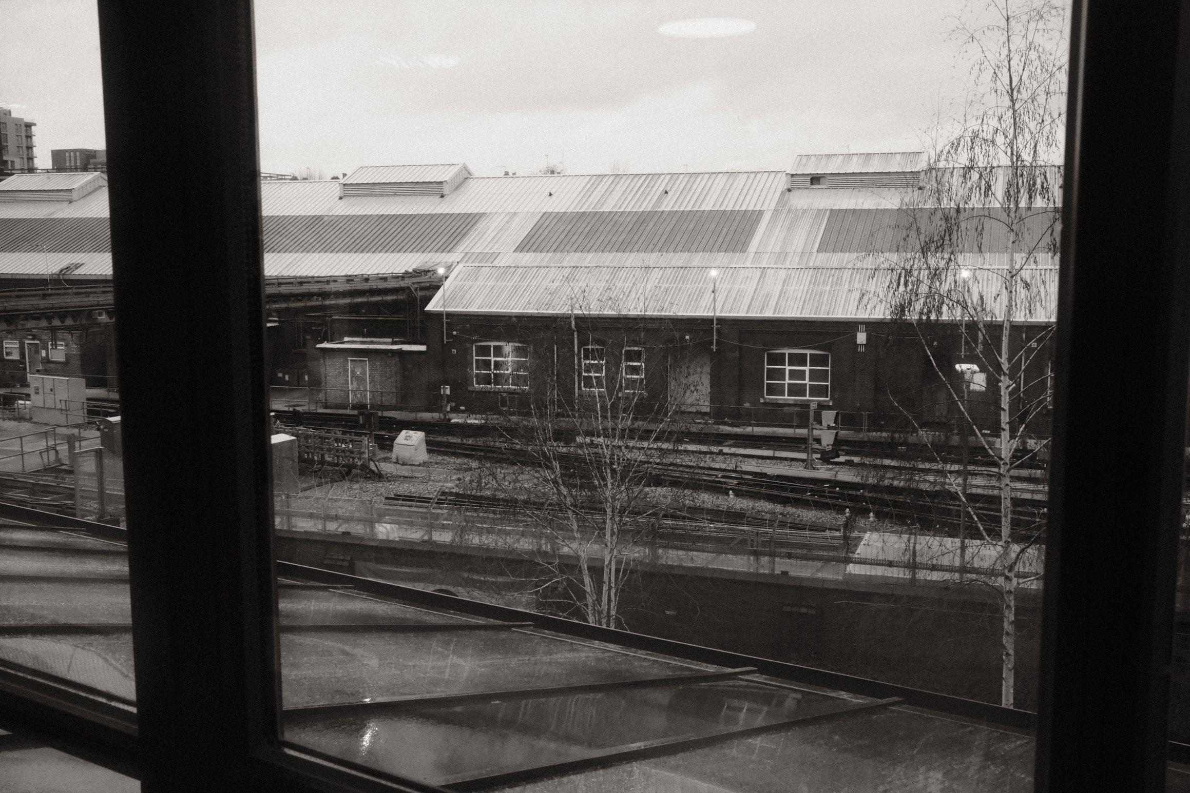 a black and white photo taken through a window looking out over railway tracks