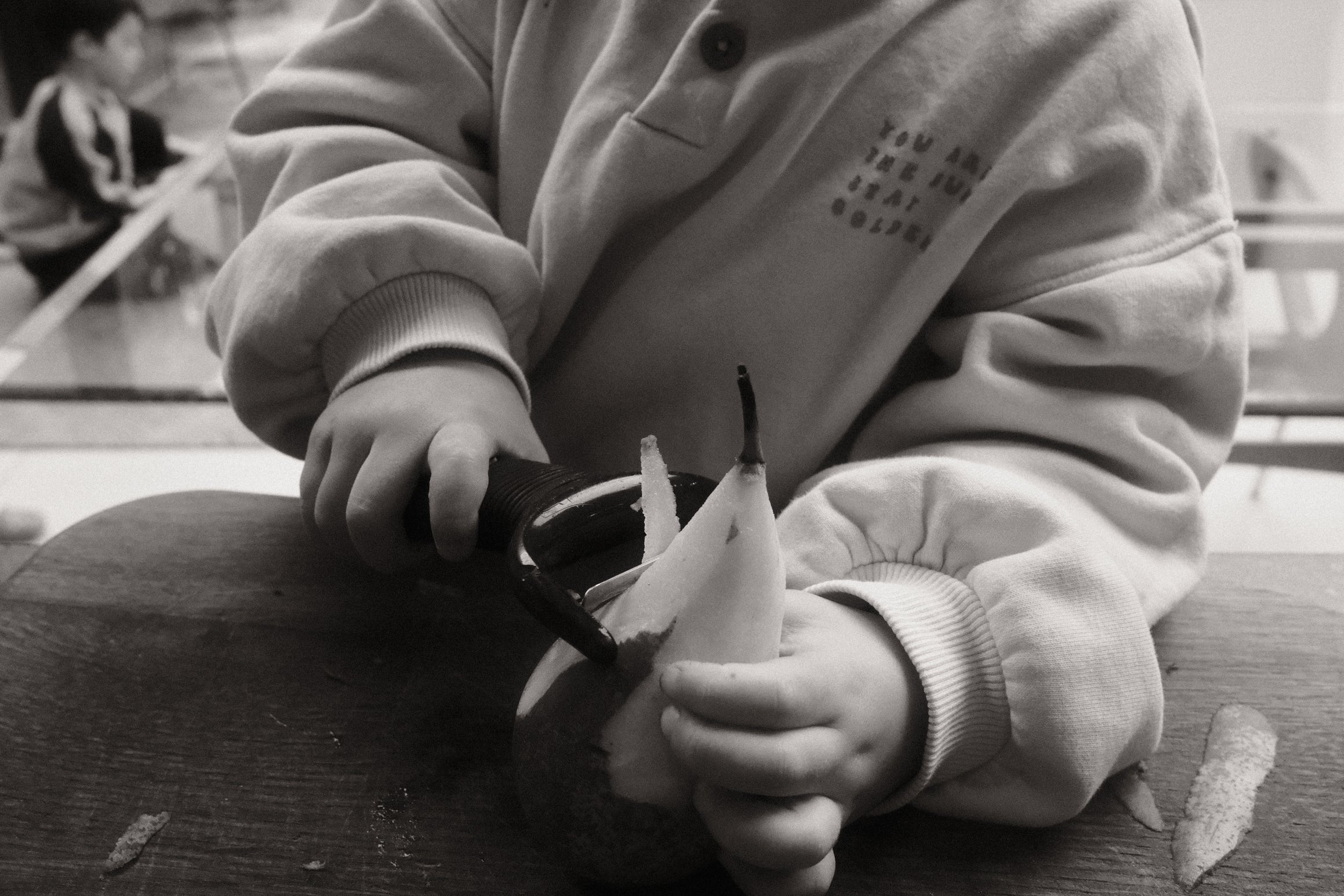 a young child peels the skin off a pear