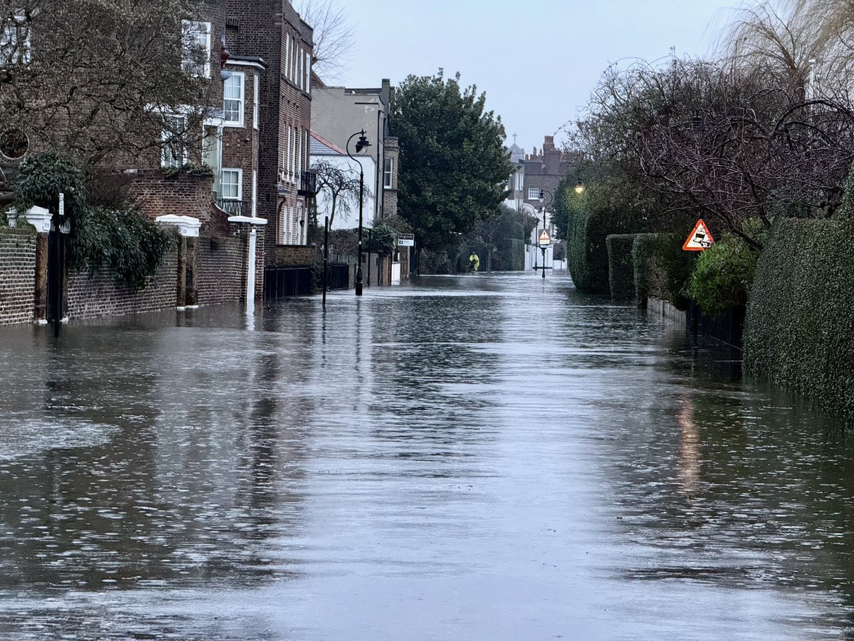 A photo of a flooded road. Flooding completely covers the road surface.