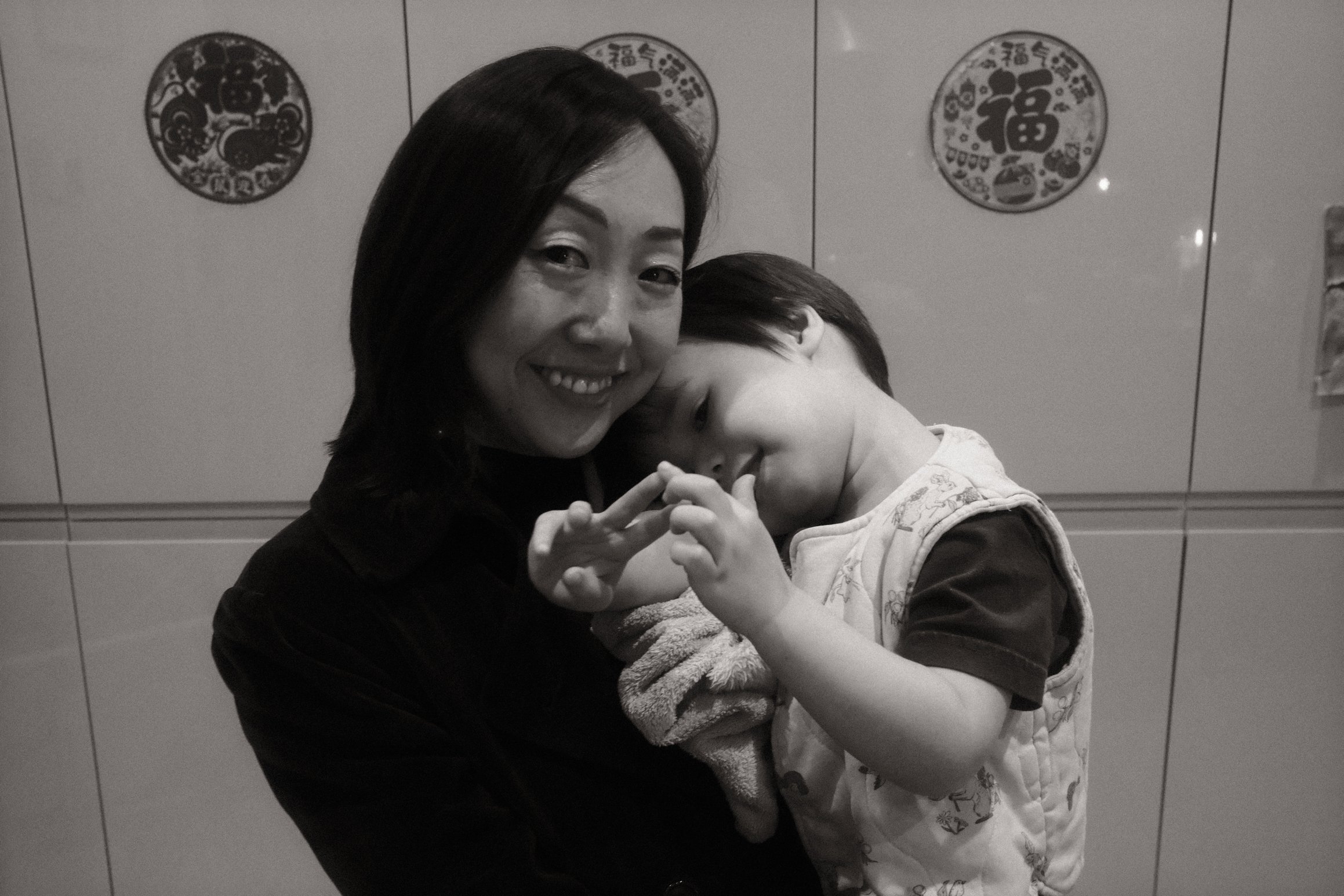 a black and white photo of a mother and child, in the background Chinese New Year decorations