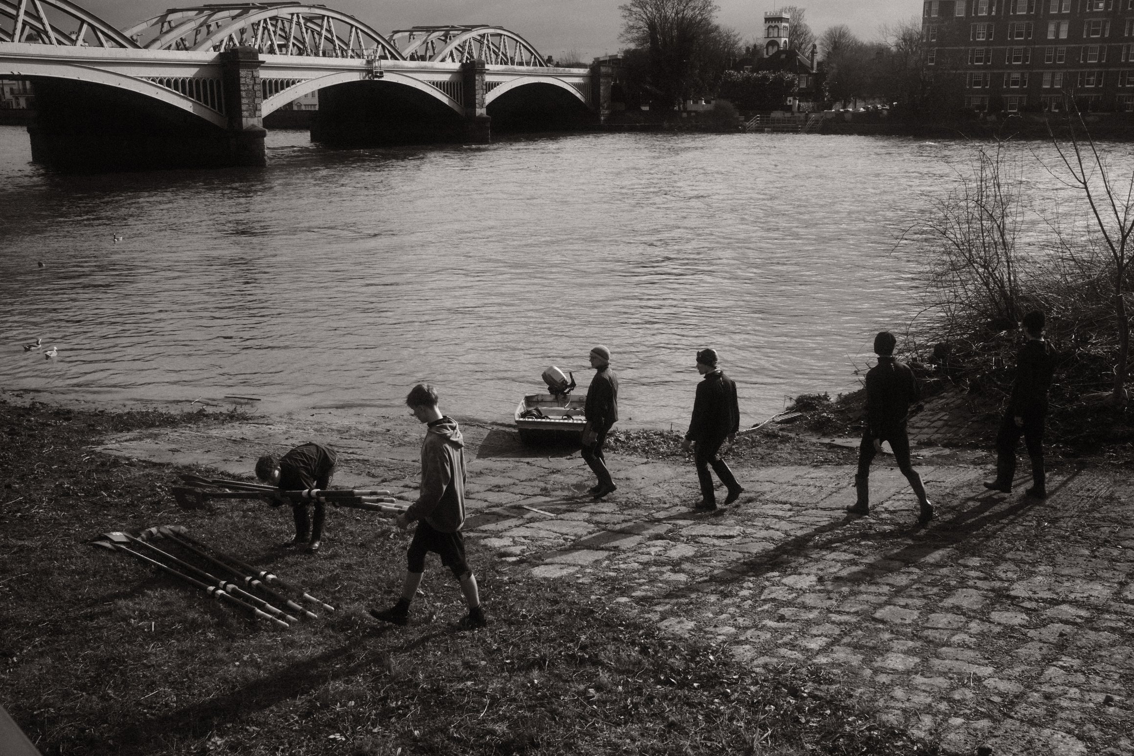 black and white photo of rowers collecting their oars on a slipway near Barnes Bridge