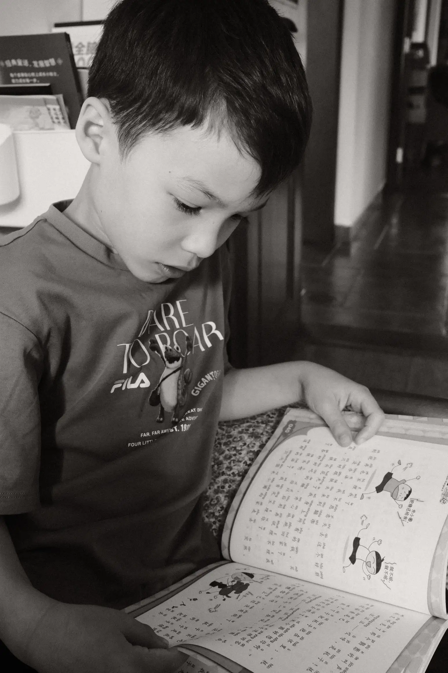 A black and white photo of a boy reading a Chinese book.