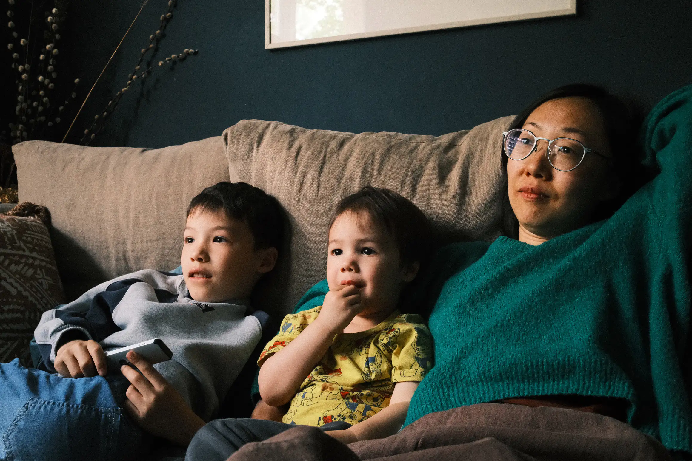 a family sits on a sofa looking at a TV thatt is off camera