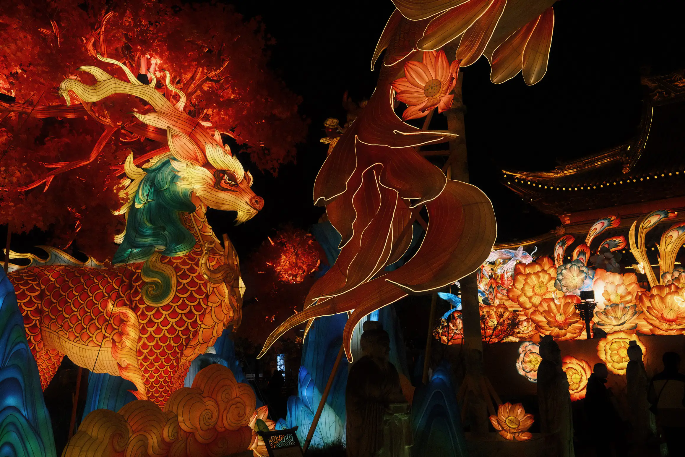 night sky lit up by large light sculptures featuring flowers and a horse