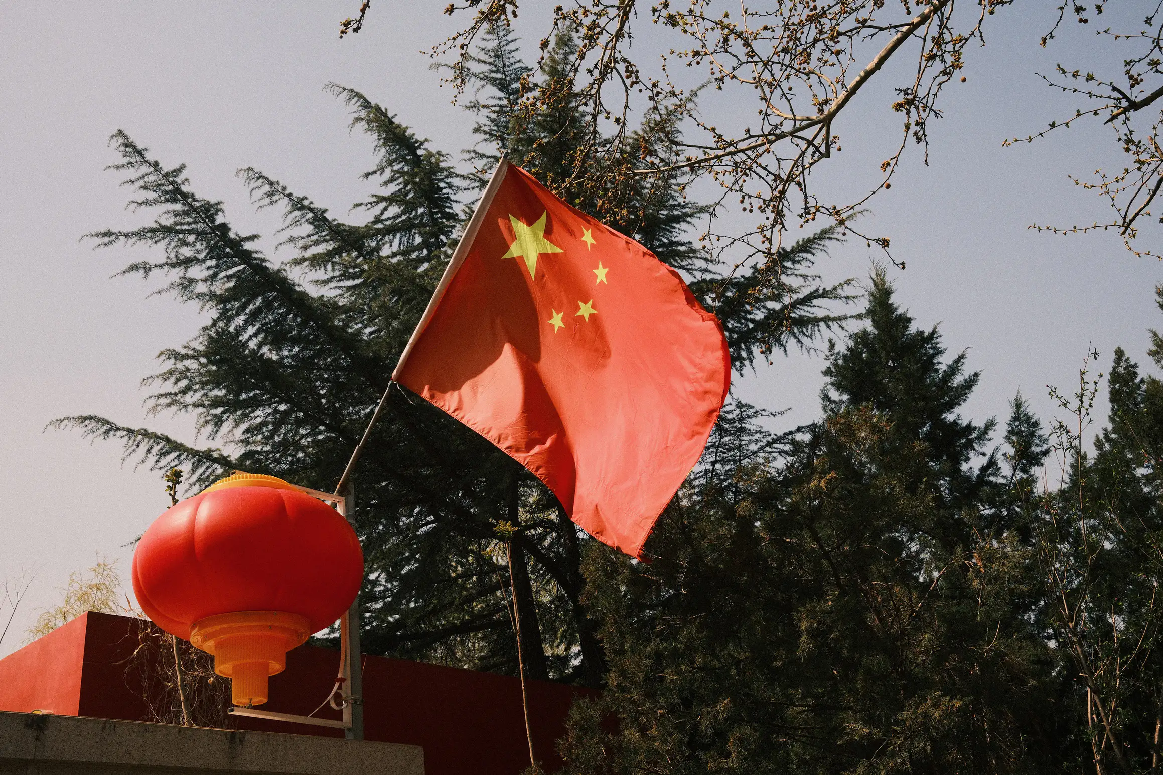 the chinese flag waves above the entrance to a residential compound