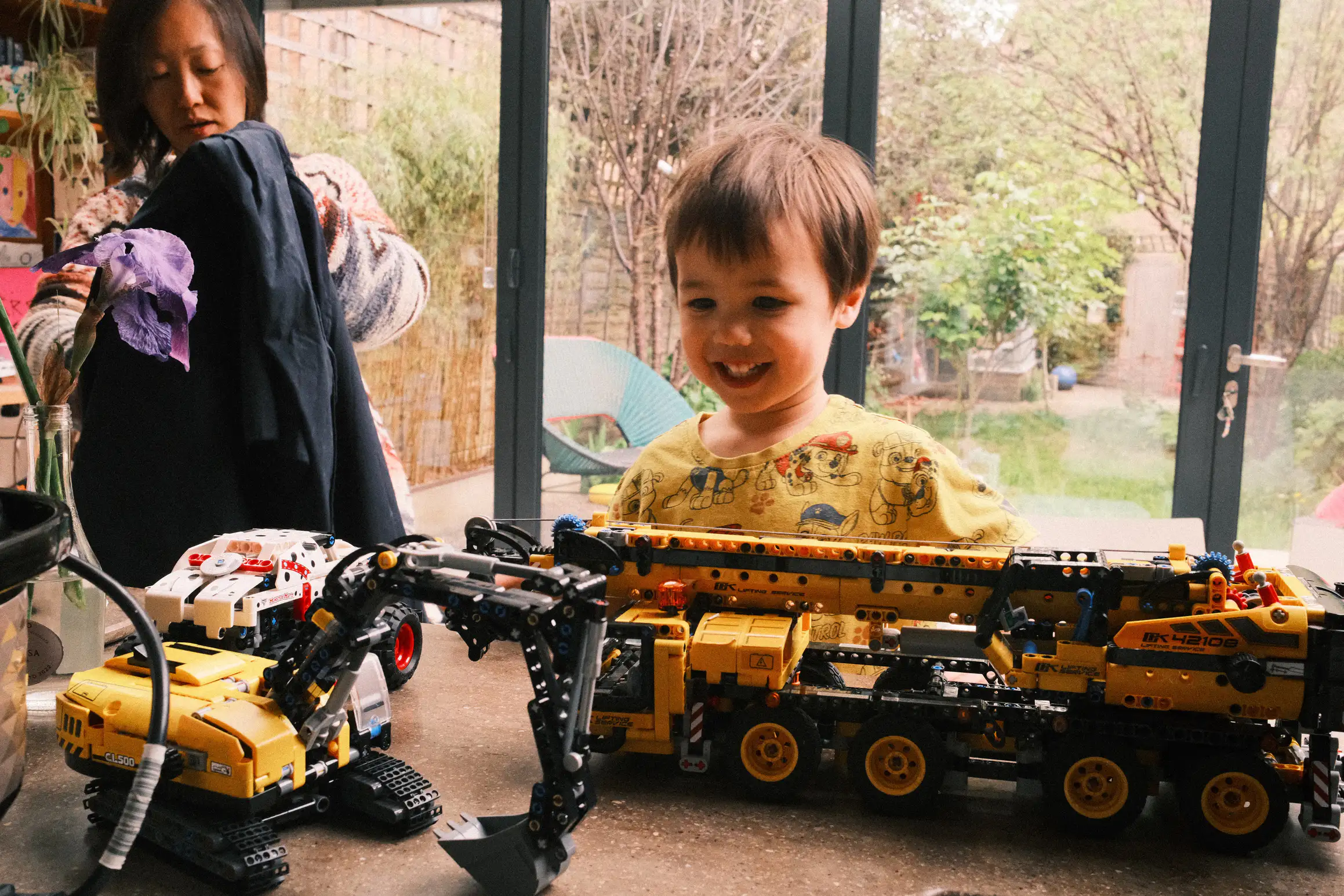 a young boy looks at a collection of Lego Technic models, a smile on his face