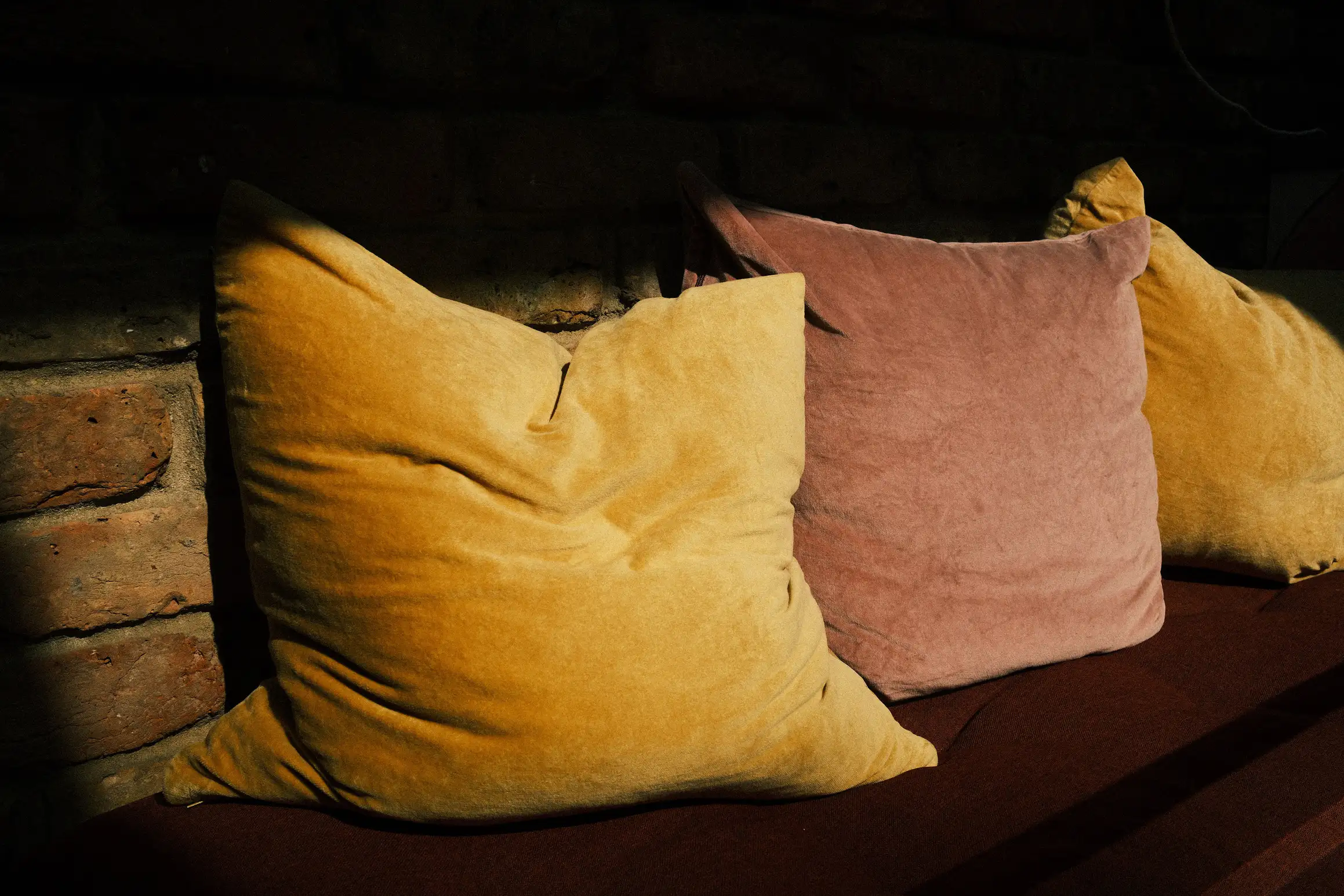 three cushions against a brick wall bathed in sunlight