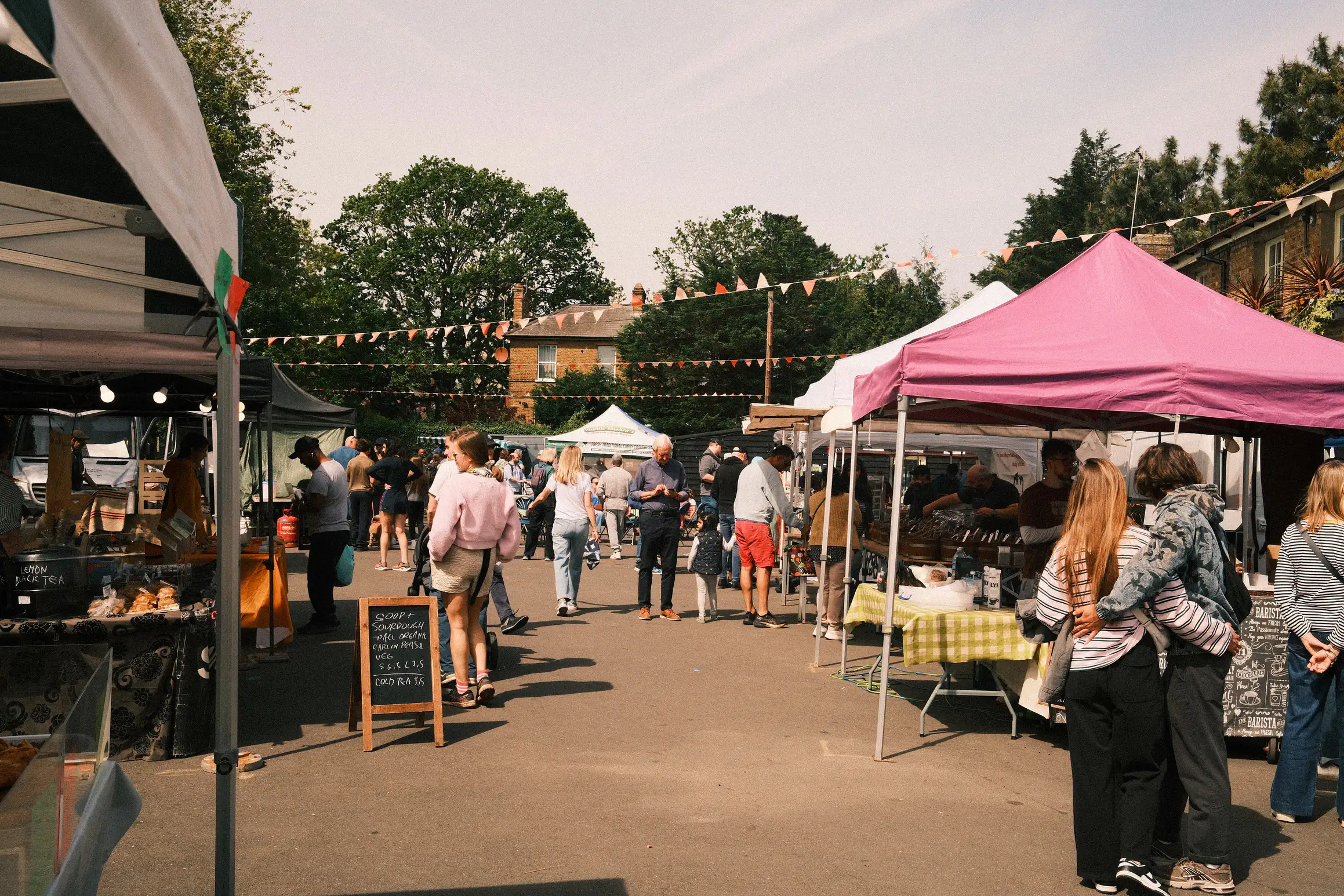 a small paved area lined by market stalls, bunting strung up between the stalls