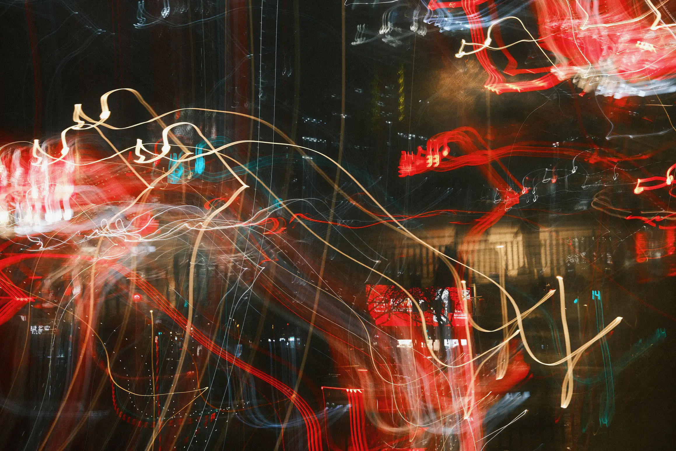 A blurred mess of light streaks across a nighttime city photo, the dominate colours are red, white, and black.