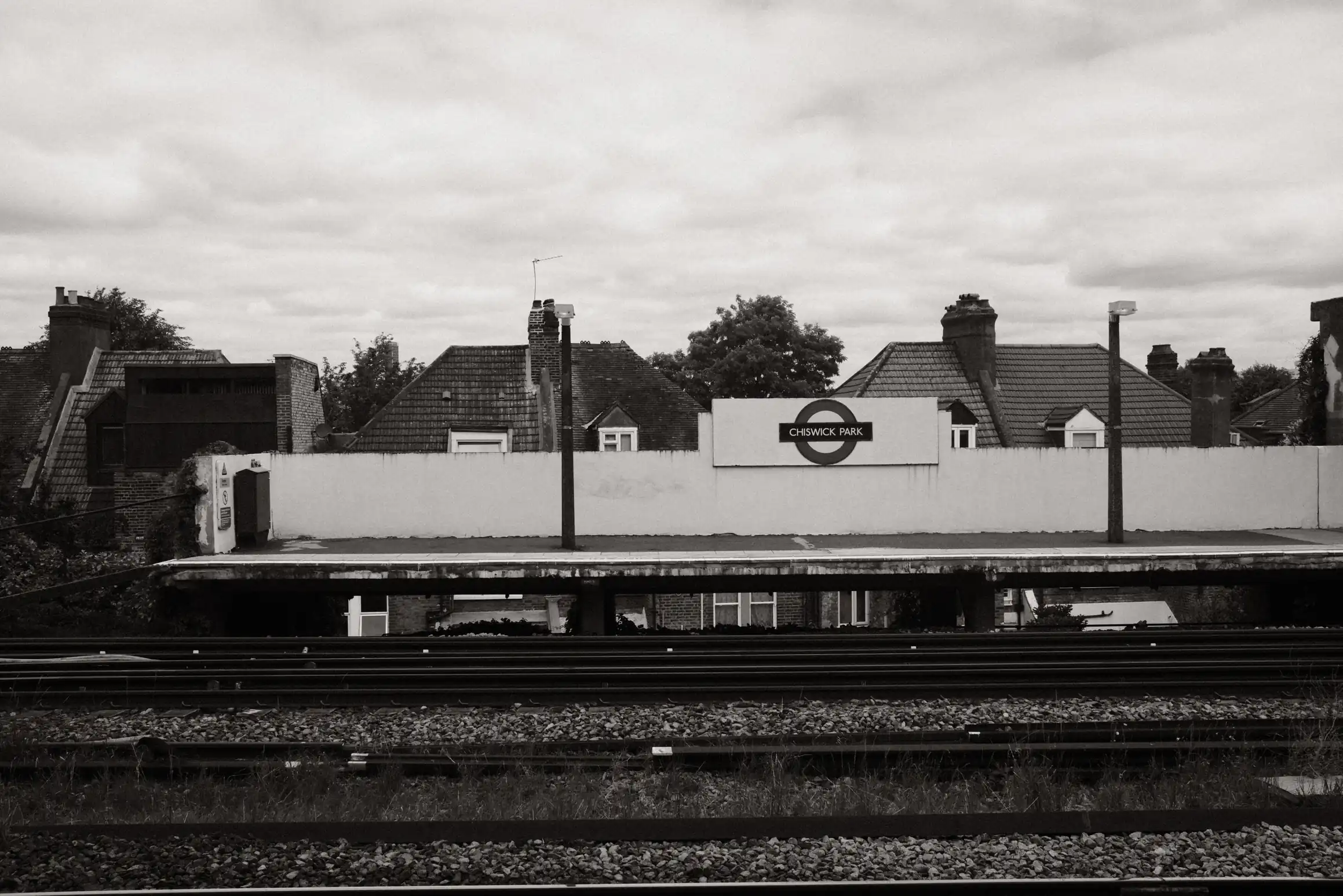 A black and white photo of a London Underground station. This station is above ground. The station name is Chiswick Park.