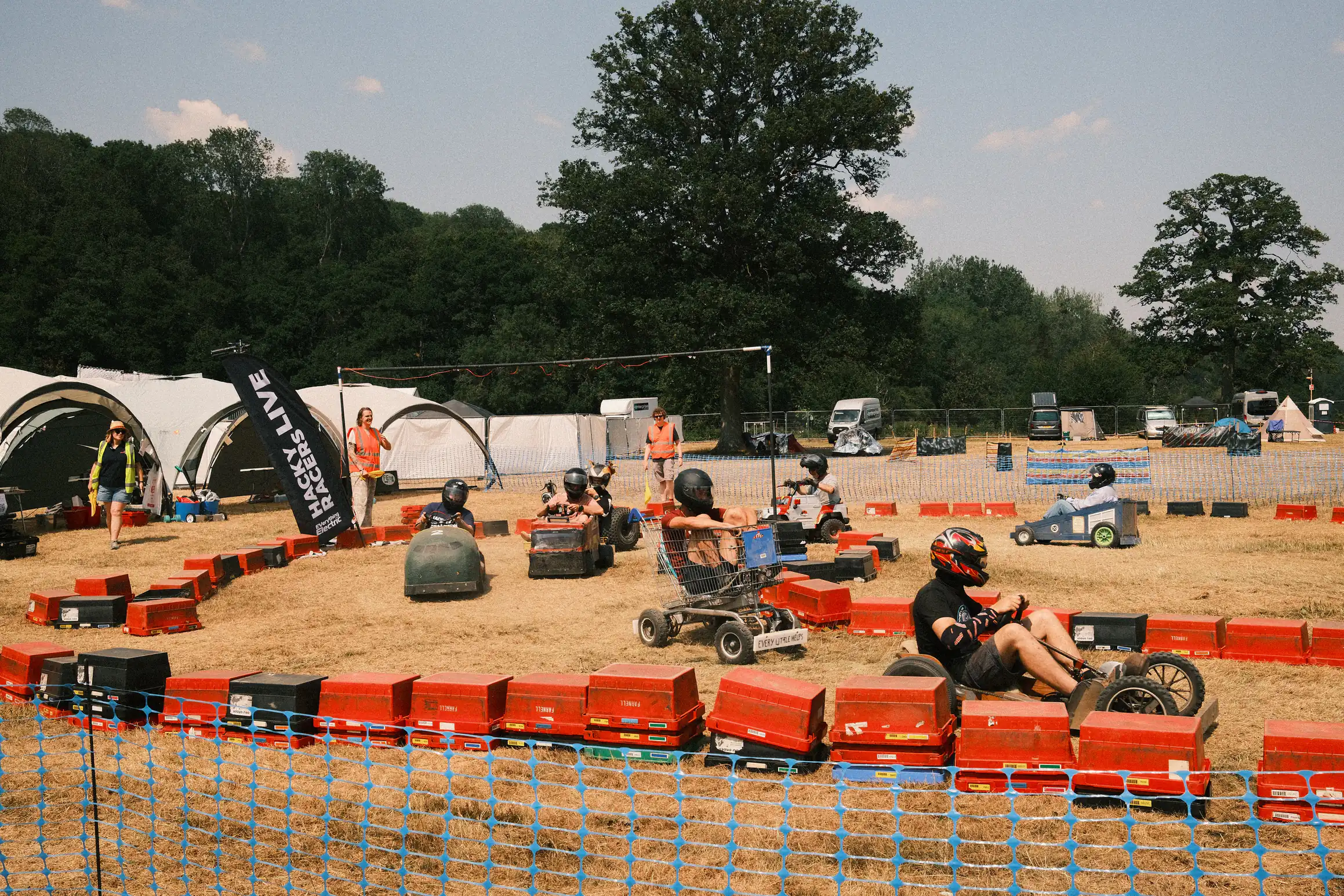 A makeshift racetrack made out of upturned crates around the racetrack several custom built vehicles race each other in the dusty ground 