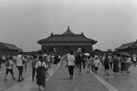 A black and white photo showing the crowds of people visiting the Temple of Heaven in Beijing. The crowd have their backs to the camera heading towards the temple gate. The photo was taken at the height of summer. The image is a scan of a negative developed at home in Ilfosol3 (1+9).
