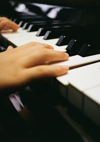 A close up of a person playing a piano. Only their hands are visible.