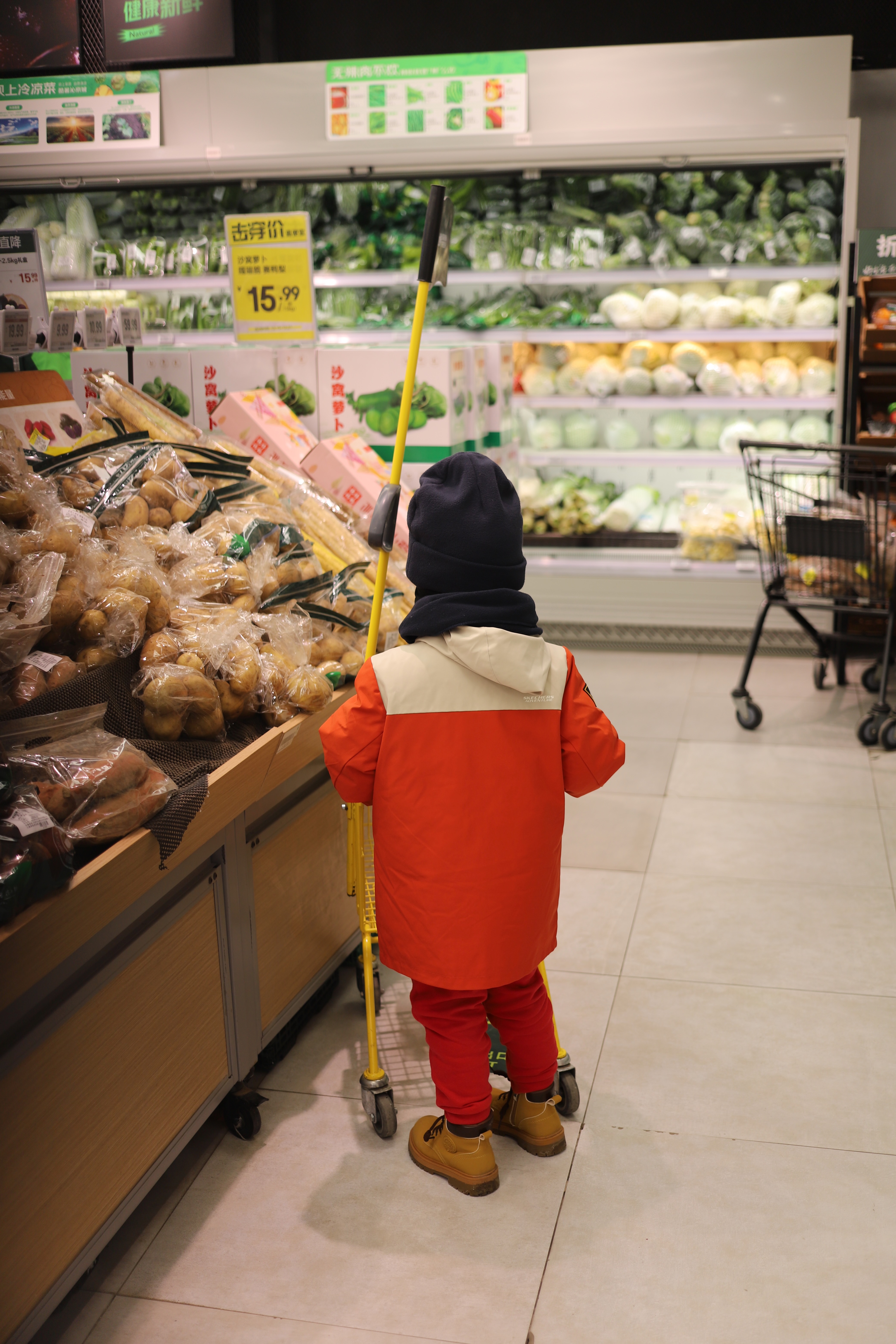My son pushing a child sized supermarket trolley around the fresh food section of the local supermarket.
